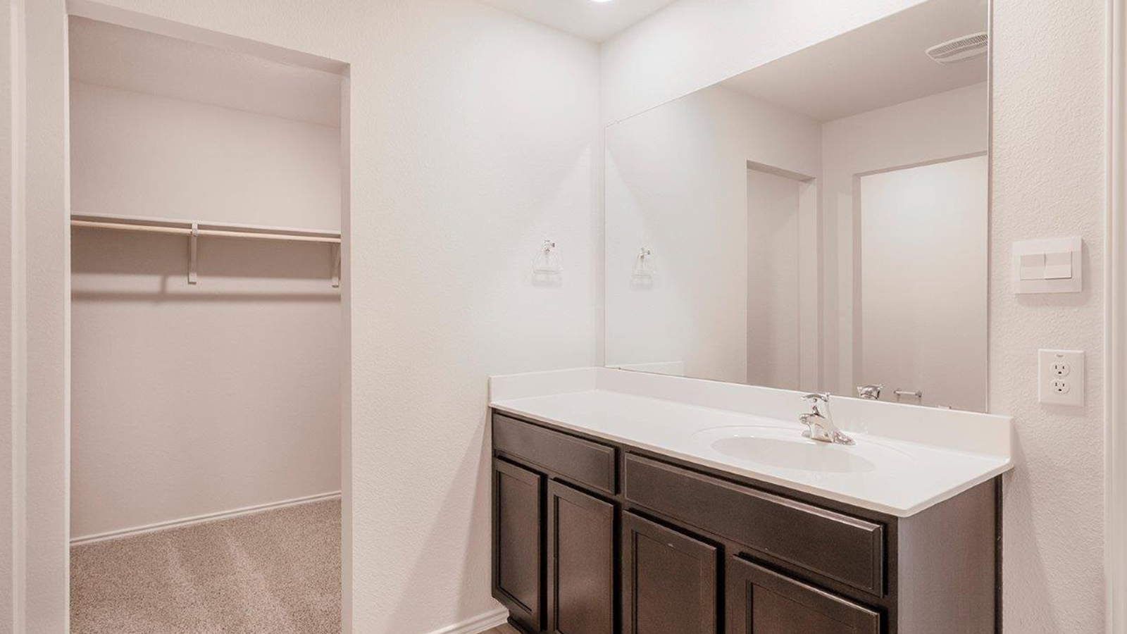 Schwertner Ranch primary bathroom with single vanity and view of primary closet.