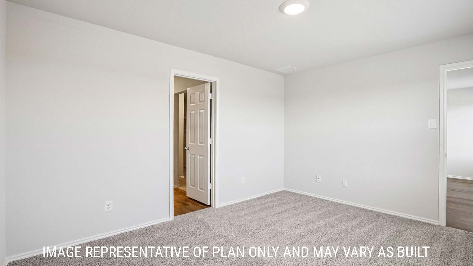Estero primary bedroom with carpeted flooring and view of primary bathroom.