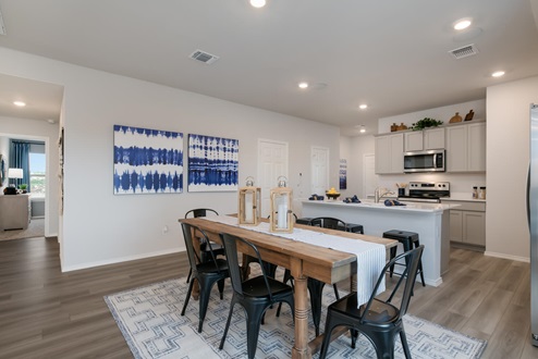 Willow Glenn model home dining room with table and view of kitchen.
