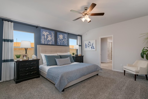Willow Glenn model home primary bedroom with a king bed and view of primary bathroom.
