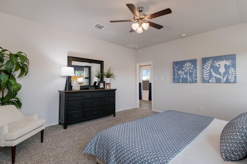 Willow Glenn model home primary bedroom with a king bed and carpet flooring.