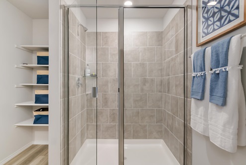 Willow Glenn model home primary bathroom with storage shelving and walk-in shower.