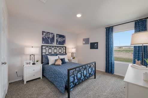 Willow Glenn model home secondary bedroom with a full-size bed and carpet flooring.