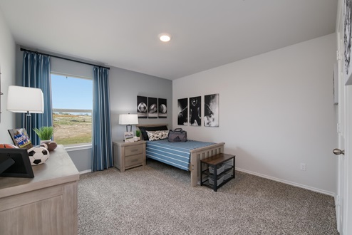 Willow Glenn model home secondary bedroom with a twin bed and carpet flooring.
