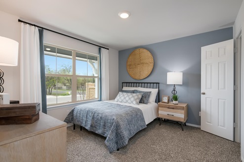 Willow Glenn model home secondary bedroom with full-size bed and accent decor.