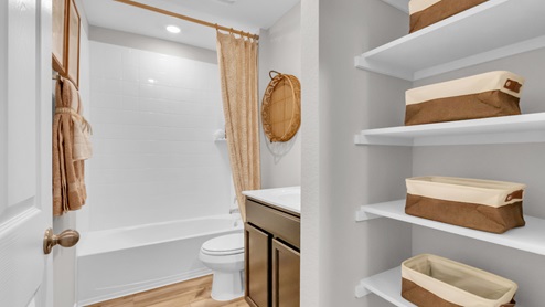 Pecan Creek model home secondary bathroom with storage shelving, along with tub and shower combo.