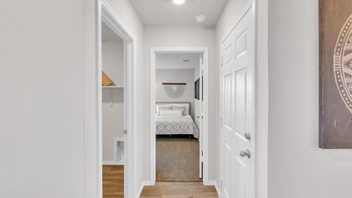 Pecan Creek model home hallway entry with a view into the secondary bedroom.