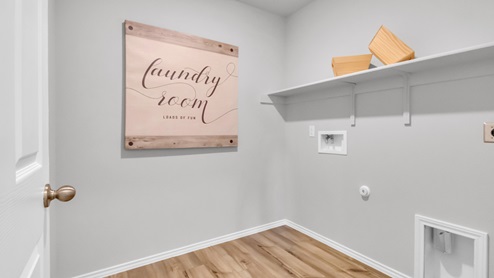 Pecan Creek model home utility room with storage shelving and washer and dryer connections.