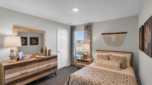 Pecan Creek model home secondary bedroom with a full-size bed and window.
