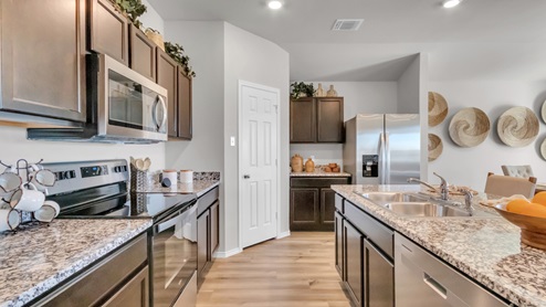 Pecan Creek model home kitchen with dark cabinets and granite countertops.