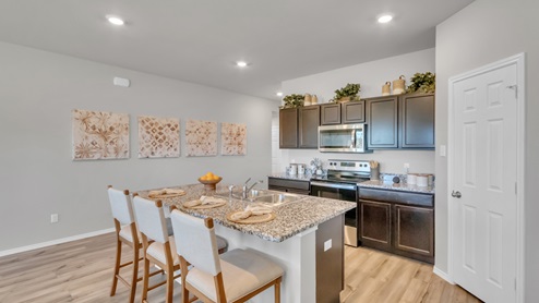 Pecan Creek model home kitchen with dark cabinets and granite countertops.