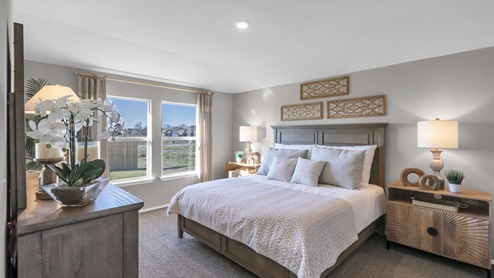 Pecan Creek model home primary bedroom with a king bed and accent decor.