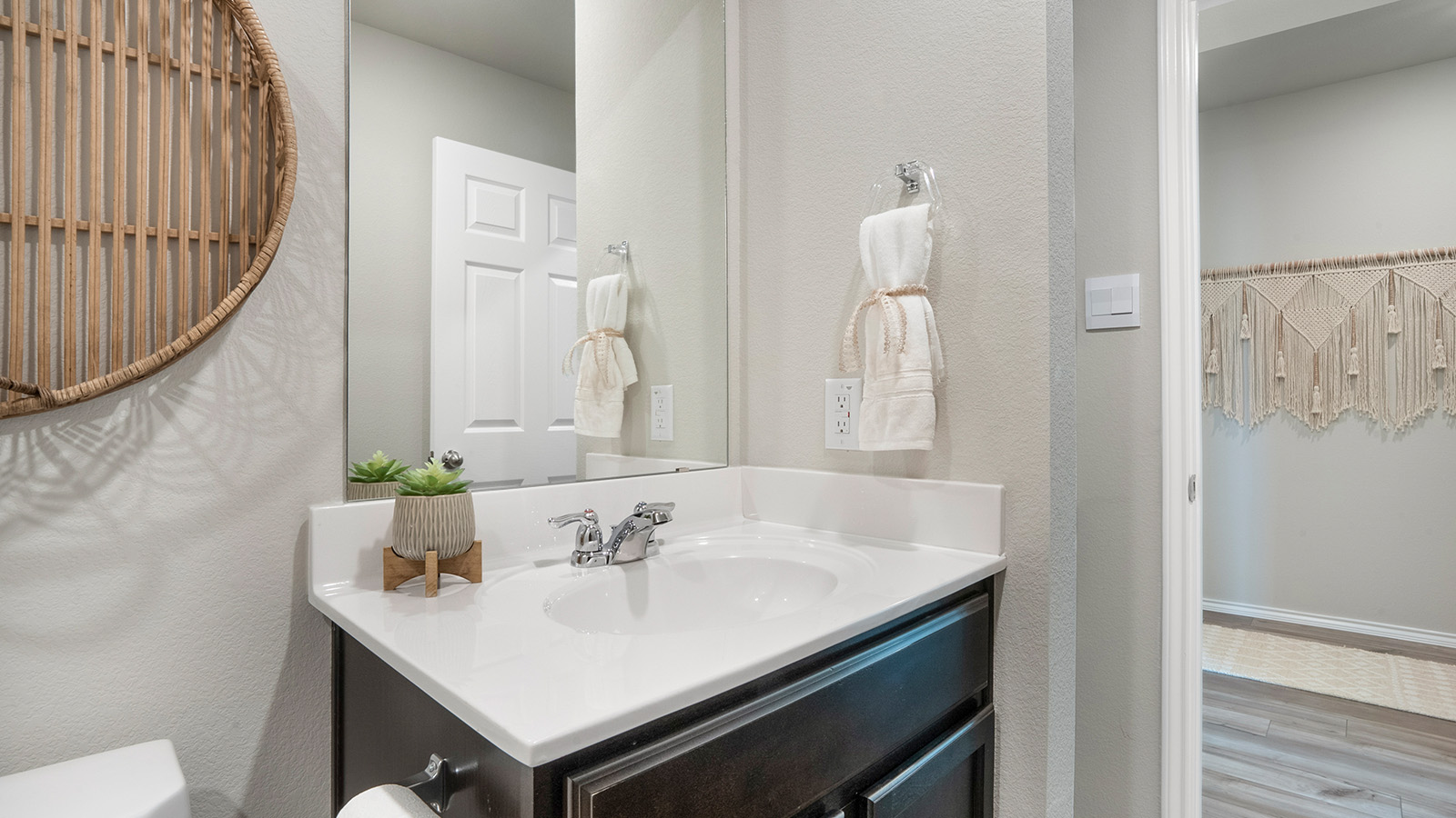 Pecan Creek Model Texas Cali secondary bathroom with sing vanity sink and view of front entrance hallway.