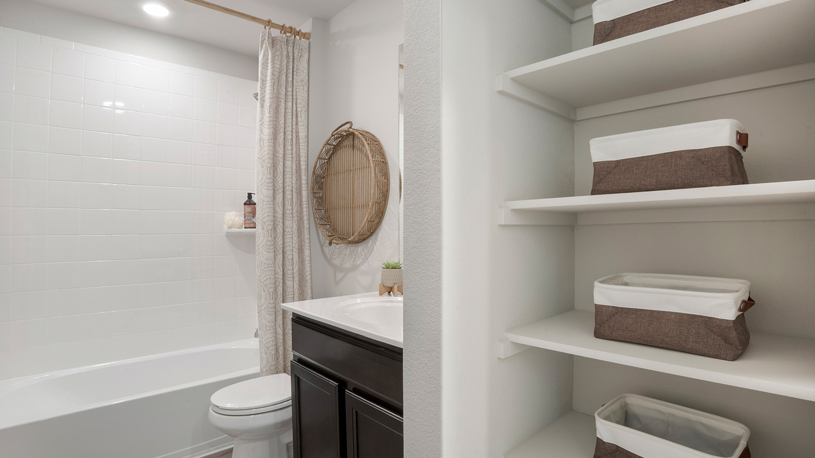 Pecan Creek Model Texas Cali secondary bathroom with shower and tub combo and shelving for storage.