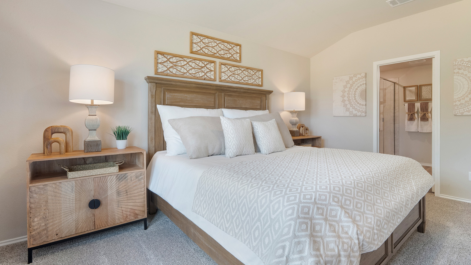 Pecan Creek Model Texas Cali primary bedroom with carpeted flooring and view of primary bathroom.