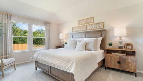 Pecan Creek Model Texas Cali primary bedroom with carpeted flooring and windows for lighting.