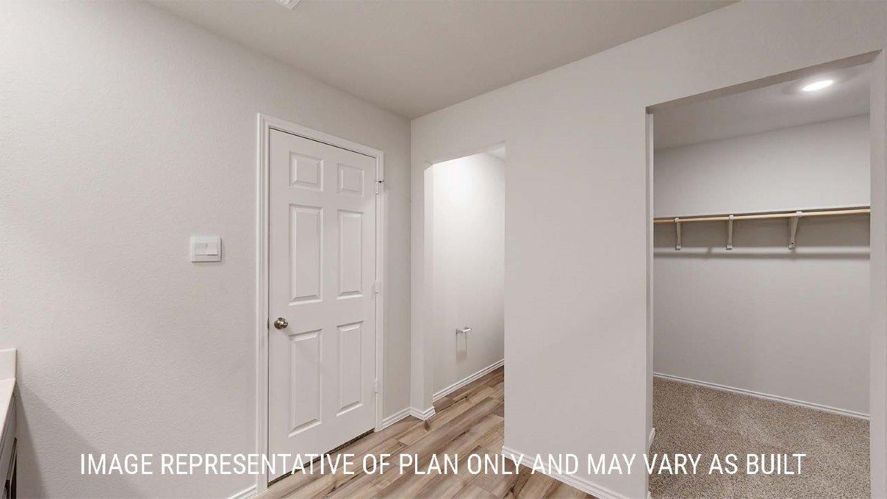 Emma primary bathroom with shelving for storage and view of primary walk-in closet.