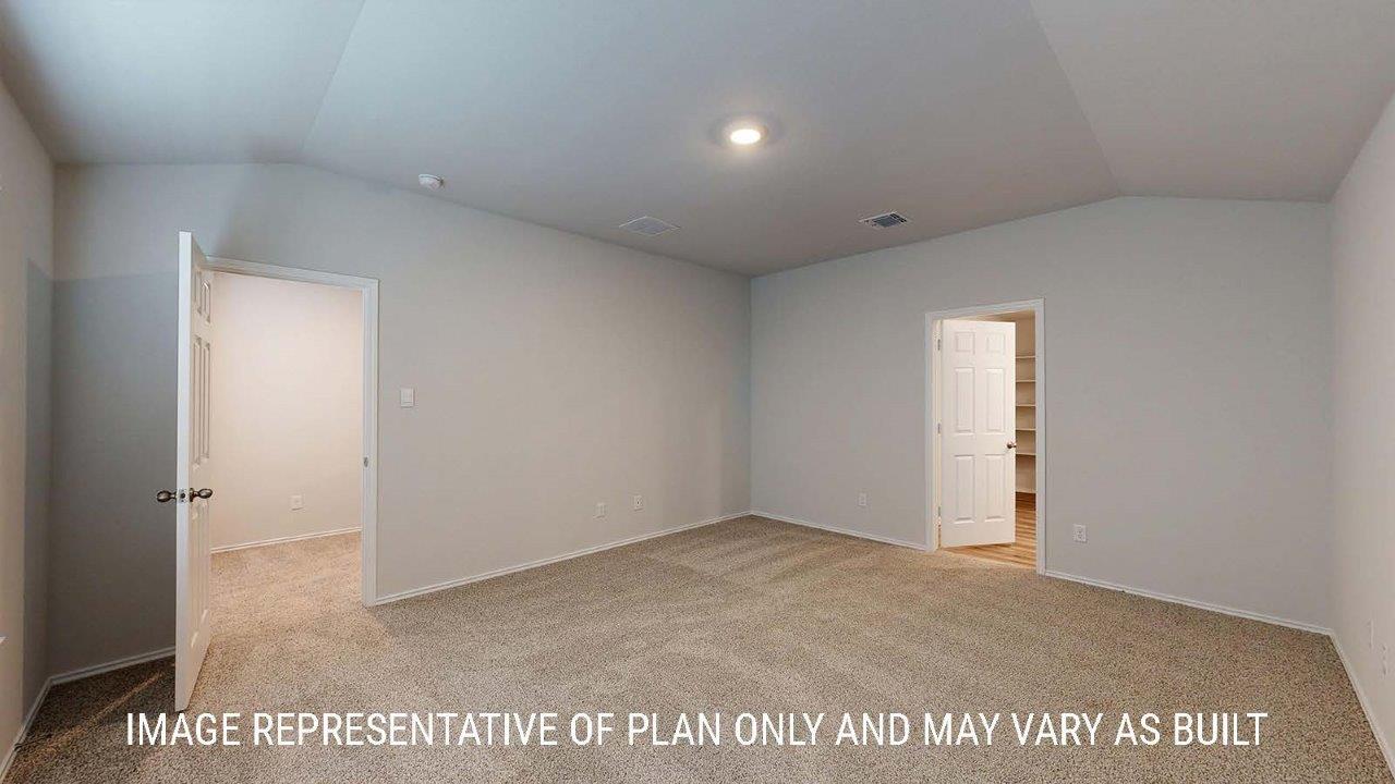 Emma primary bedroom with carpeted flooring and view of primary bathroom.