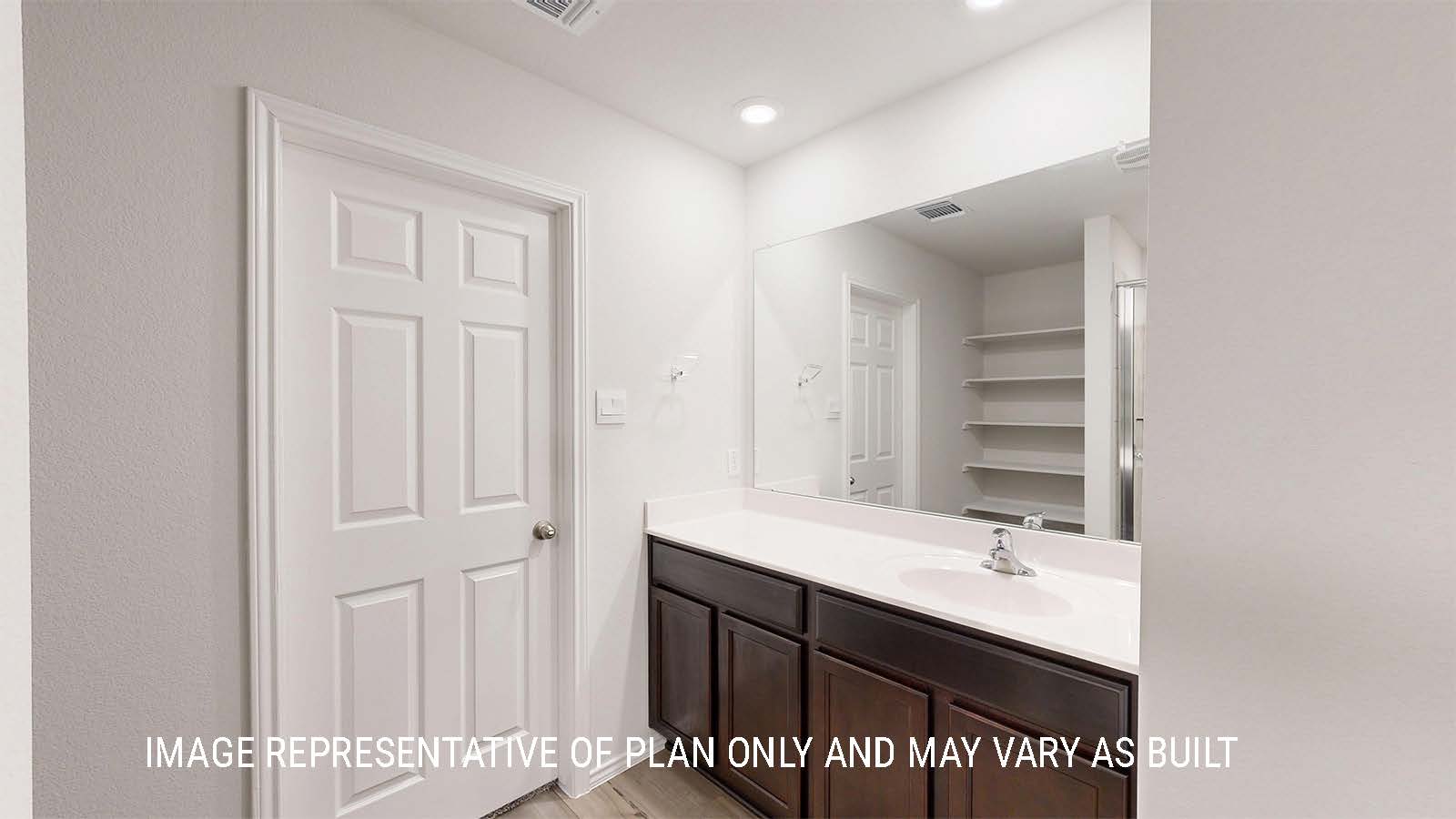Grace primary bathroom with single vanity with dark cabinets and mirror.