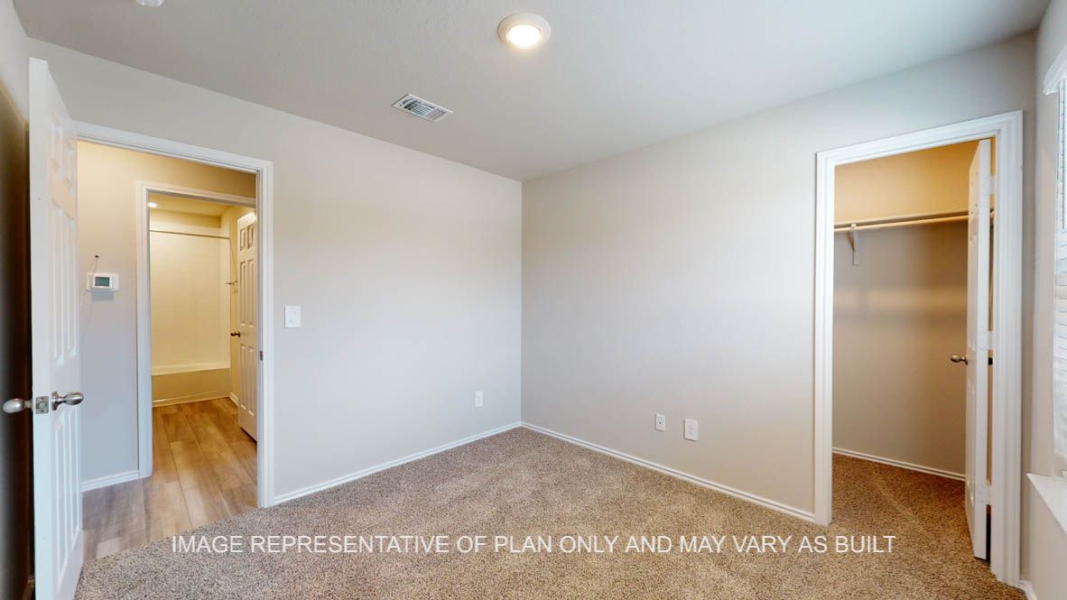 Fargo primary bedroom with carpet flooring and walk-in closet.