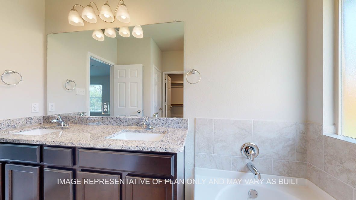 Richmond primary bathroom with garden tub and dual vanity sink with granite countertops and dark cabinets.
