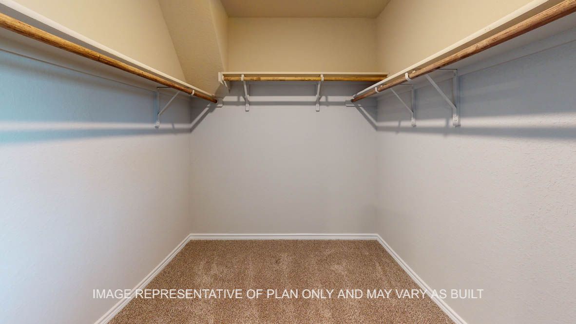 Kiawa primary bedroom walk-in closet with carpet flooring and ample hanging and shelf space.