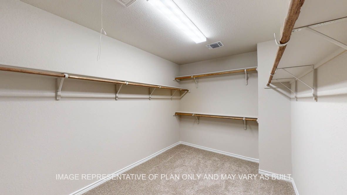 Kiawa primary bedroom walk-in closet with carpet flooring and ample hanging and shelf space.