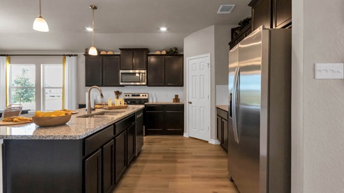 Warrior's Legacy model home kitchen with dark cabinets and granite countertops.