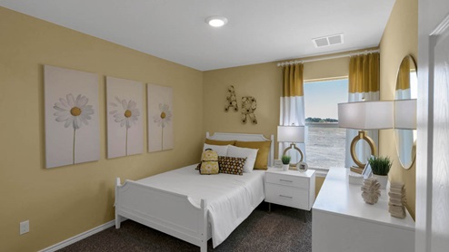 Warrior's Legacy model home secondary bedroom with a full-size bed and carpet flooring.