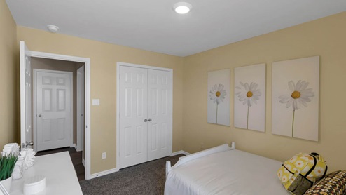 Warrior's Legacy model home secondary bedroom with a full-size bed and view of double closet doors.