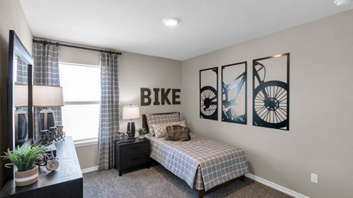 Warrior's Legacy model home secondary bedroom with a twin bed and accent decor.