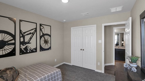 Warrior's Legacy model home secondary bedroom with a twin bed and view of closet door.