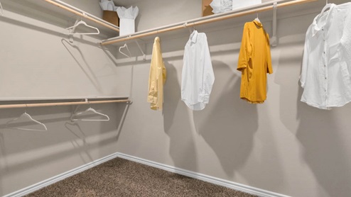 Warrior's Legacy model home primary closet with spacious room and carpet flooring.