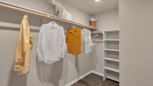 Warrior's Legacy model home primary closet with storage shelving and carpet flooring.