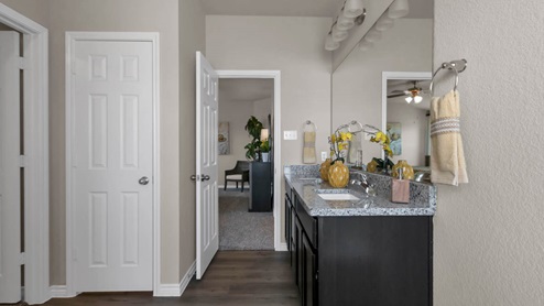 Warrior's Legacy model home primary bathroom with double vanity sinks and mirror.
