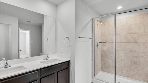 Lake Pointe Terrace primary bathroom with double vanity sink and walk-in shower.