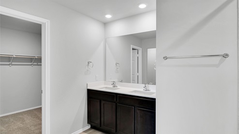 Lake Pointe Terrace primary bathroom with double vanity sink and view of primary walk-in closet.