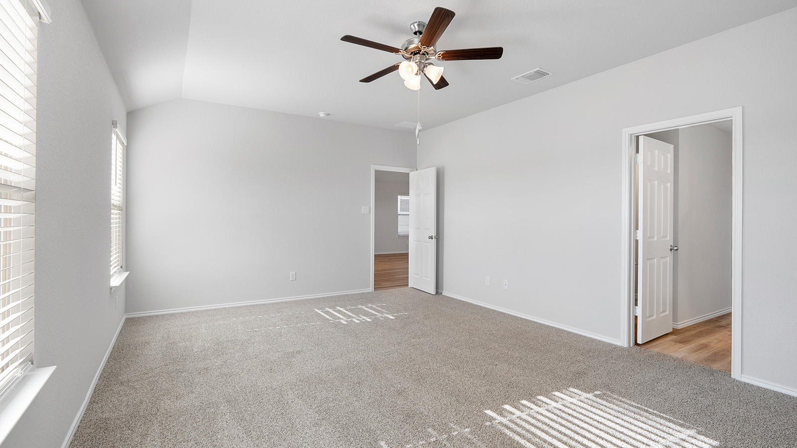 Creekside Hills model home primary bedroom with carpeted flooring and windows.