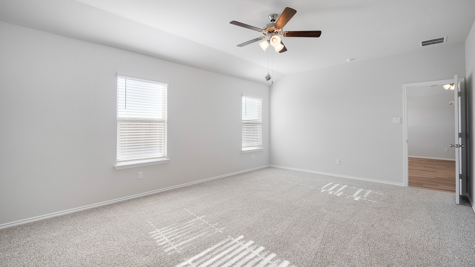 Creekside Hills model home primary bedroom with carpeted flooring and windows.