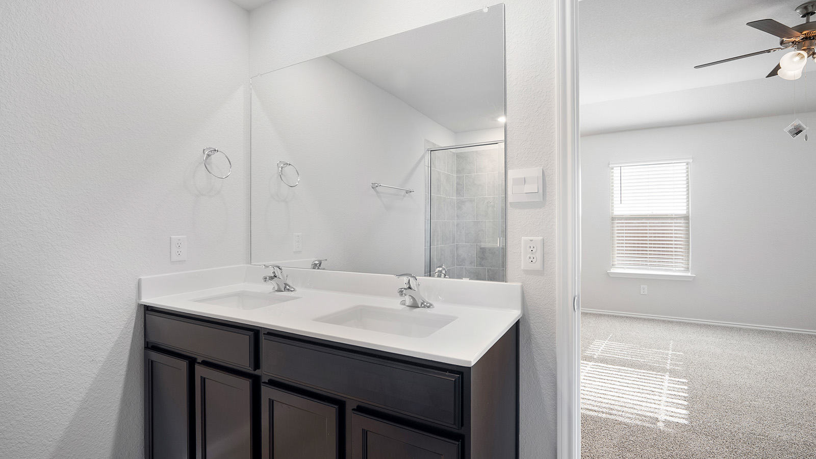 Creekside Hills model home primary bathroom with double vanity sink and view of primary bedroom.