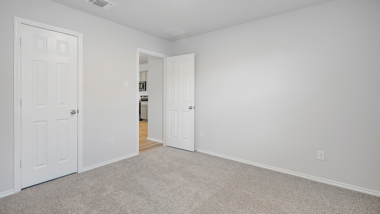 Creekside Hills model home secondary bedroom with carpeted flooring and view of kitchen.