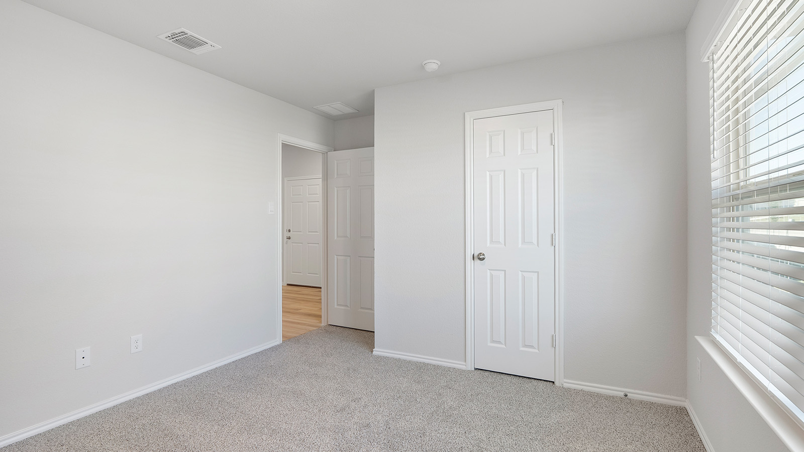 Creekside Hills model home secondary bedroom with carpeted flooring and window.