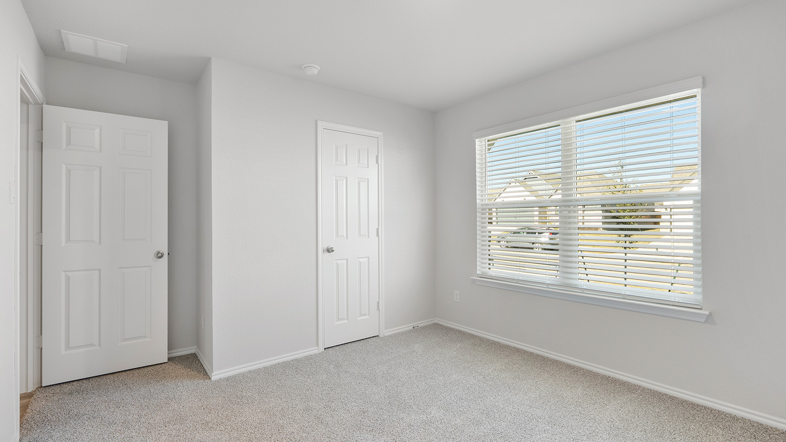Creekside Hills model home secondary bedroom with carpeted flooring and windows.