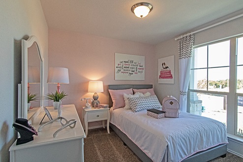 Creekside Hills model home secondary bedroom with twin bed and nightstand and window to view of front of house.