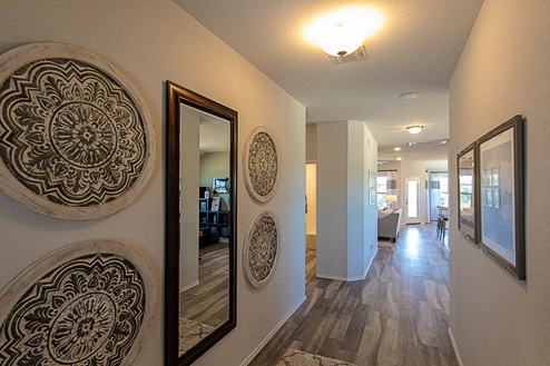 Creekside Hills model home entry with vinyl plank flooring and wall art decor.