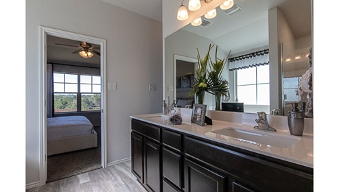 Creekside Hills model home primary bathroom with dark cabinets and white countertops.