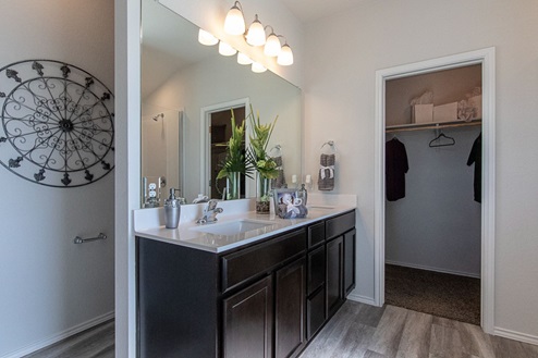 Creekside Hills model home primary bathroom with dark cabinets and white countertops.
