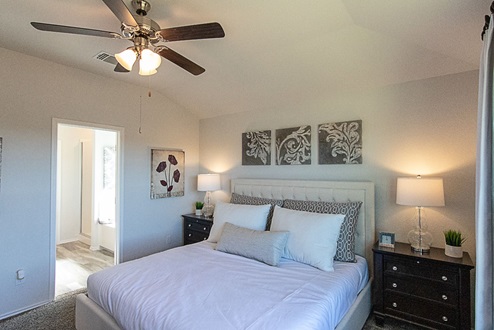 Creekside Hills model home primary bedroom with king sized bed and nightstands.