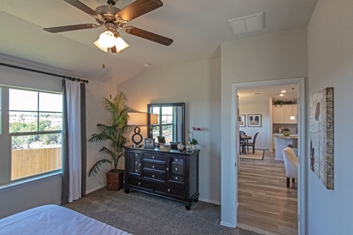 Creekside Hills model home primary bedroom with large dresser and windows offering natural lighting.