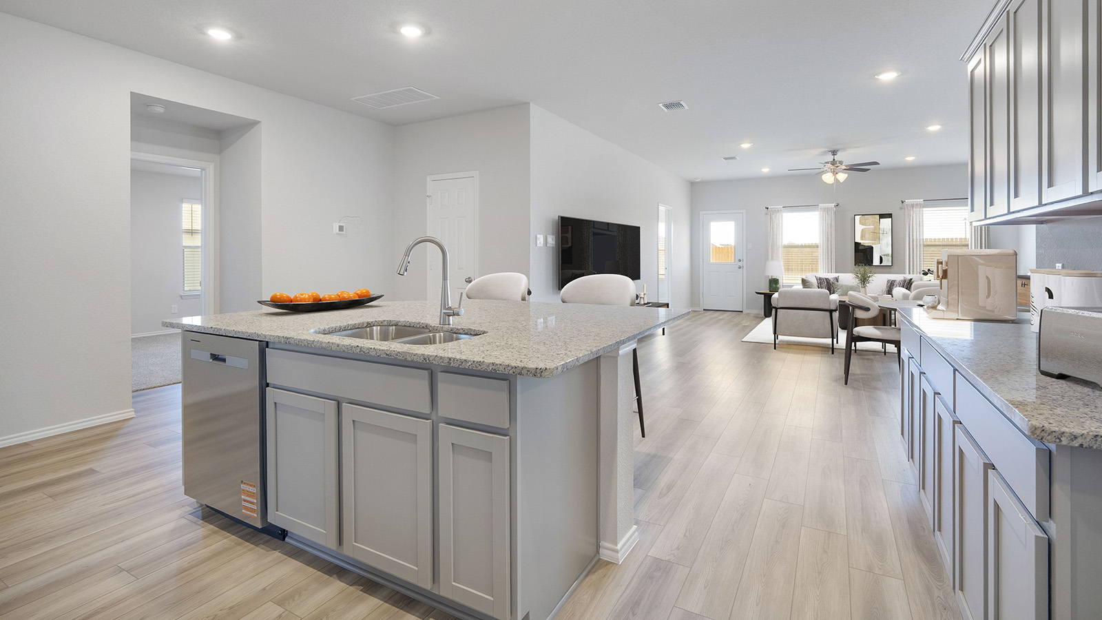 Creekside Hills model home kitchen with light cabinets and granite countertops with view of living room.